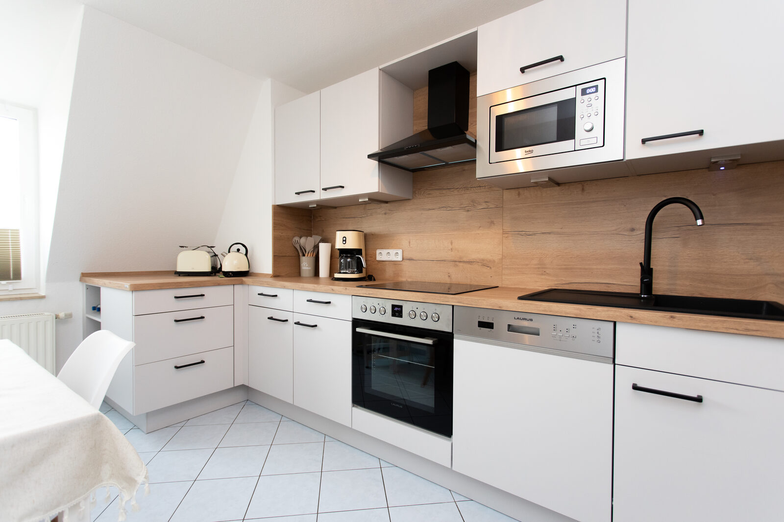 Moderne weiße Küche mit Backofen, Mikrowelle und Holz-Arbeitsplatte