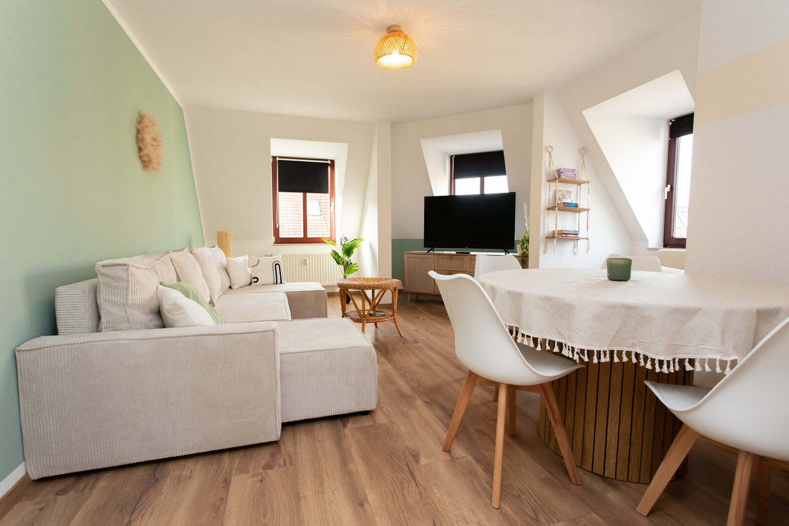 Wohnzimmer des Boho-Chic-Apartments mit Sofa, Esstisch und Dachschrägen