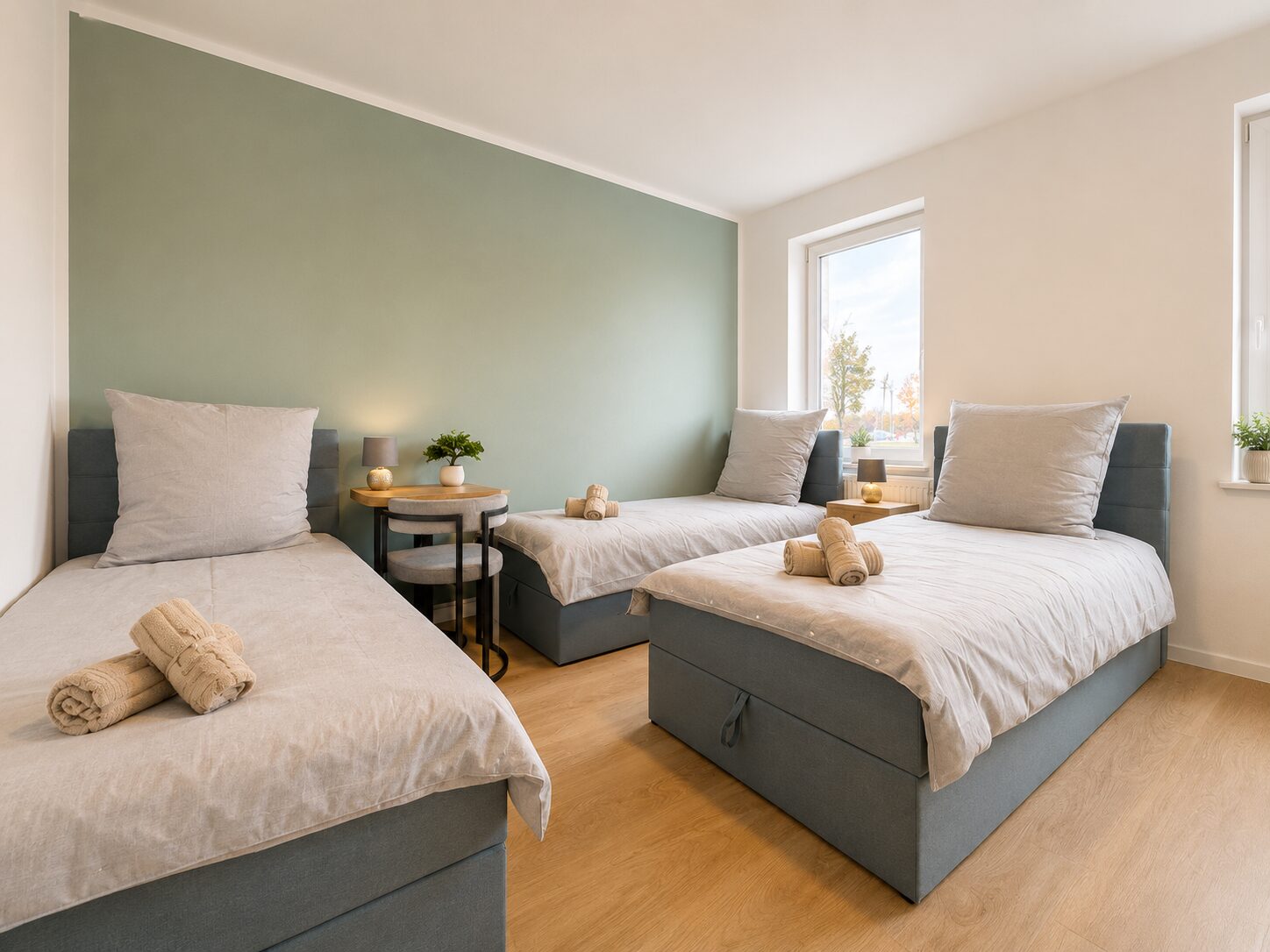 Dreibettzimmer mit drei Einzelbetten vor salbeigrüner Wand