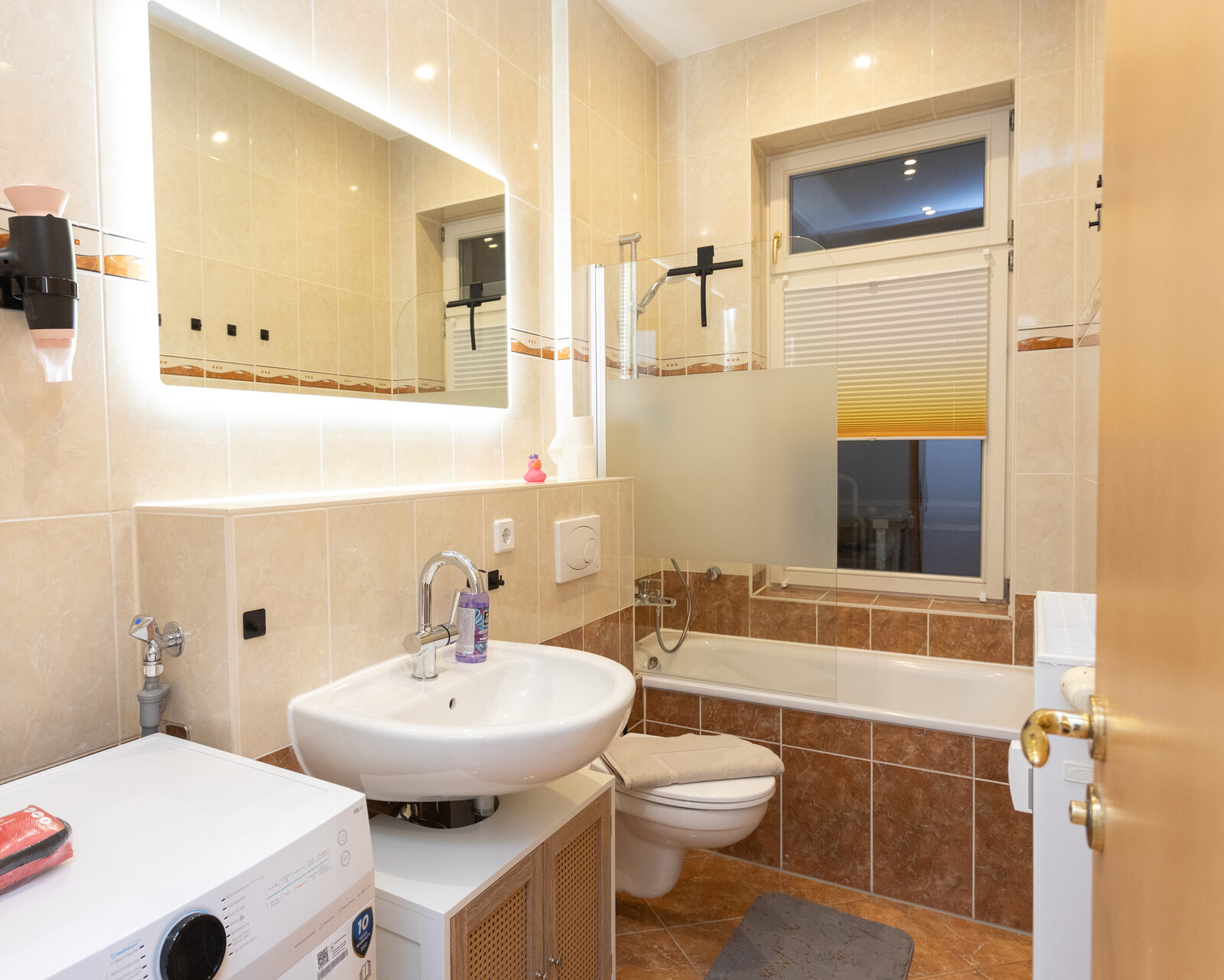 Badezimmer mit Badewanne, Waschbecken und Waschmaschine