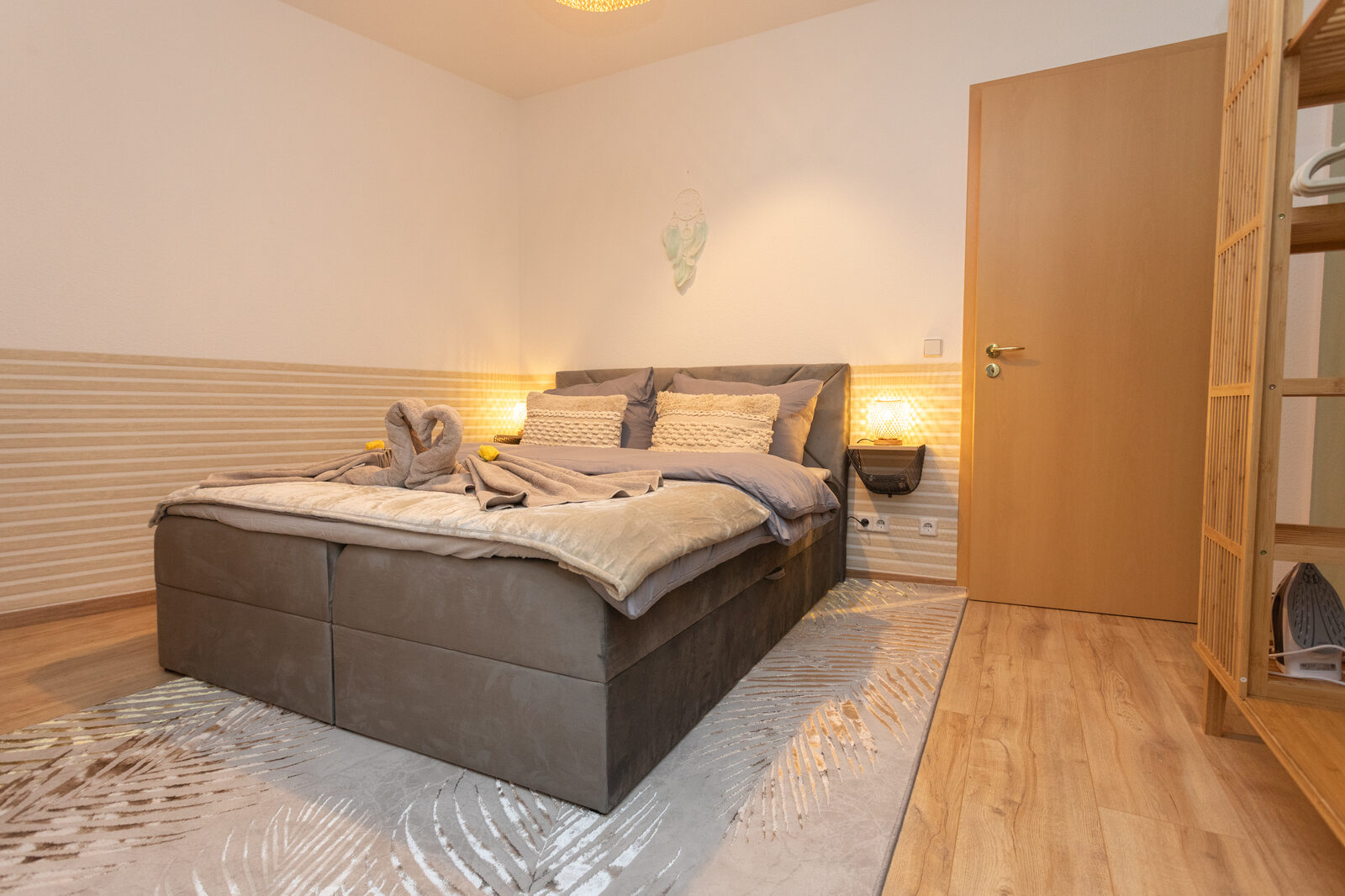 Schlafzimmer mit großem Boxspringbett und warmem Licht
