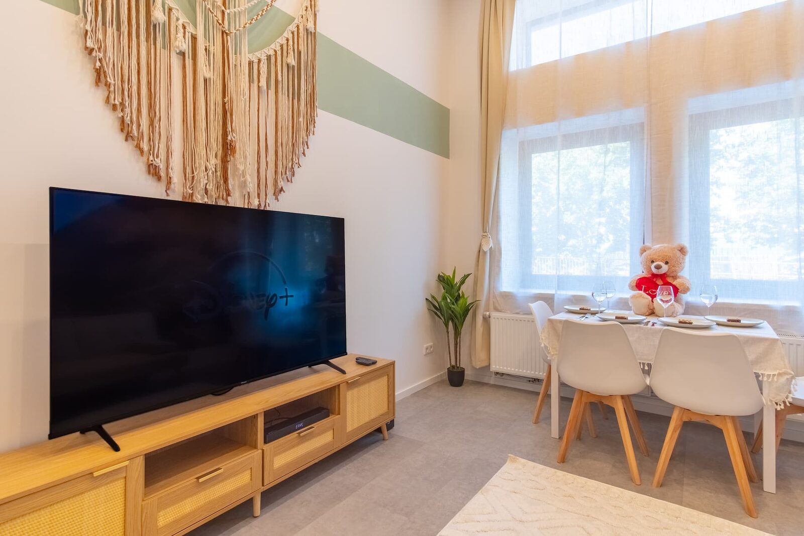 Wohnbereich des Apartments im Erdgeschoss mit großem Fernseher und Esstisch