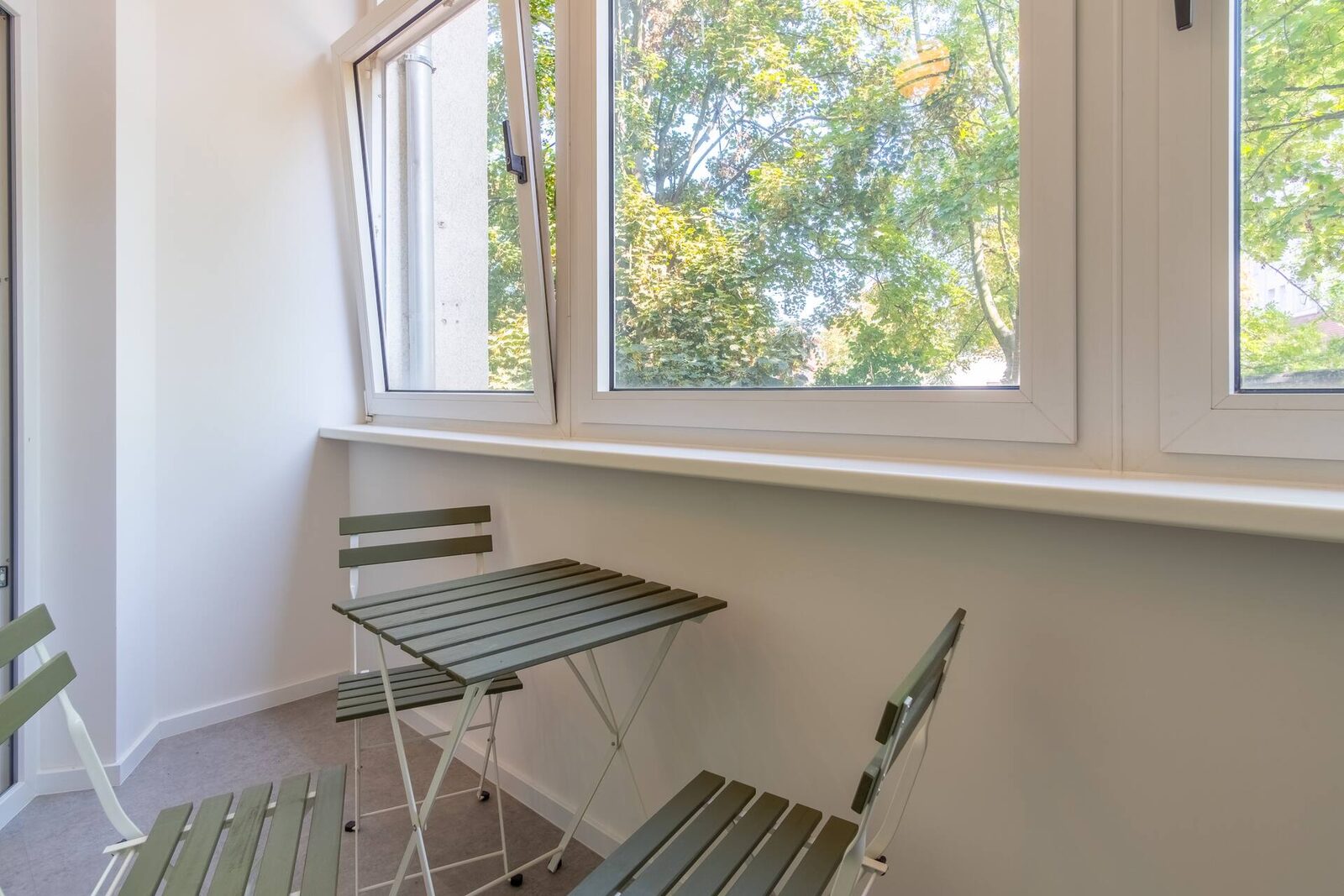 Verglaste Loggia mit Bistrotisch und Blick ins Grüne